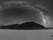 360° panorama of Racetrack Playa in Death Valley at night. The Milky Way is visible as the arc in the center. A sailing stone is also seen below along with the tracks of other stones.