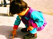 Young child playing at ease in a squatting position