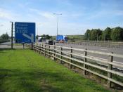 English: M1 Motorway at Toddington Services The sign shows the distance to the upcoming Junction 12 for northbound motorists. As part of creeping Europeanization the motorway is apparently now known to Brussels bureaucrats as European Route E13...