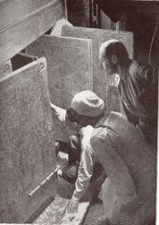 English: Howard Carter (kneeling), an Egyptian workman, and Arthur Callender at doors of burial shrines in Pharao Tutankhamen’s tomb. Magyar: Howard Carter (térdel), egy egyiptomi munkás és Arthur Callender Tutanhamon fáraó sírjának kinyitása pillanatában