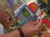 English: 'I'm Lovin It' — HM1(FMF) Fred Turner swipes his gift card in McDonald's new card machine, April 4. The new machine now allows customers to use debit, credit or gift cards to purchase food.