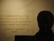 First Floor at the Statute of John Marshall in the foreground, shadowed, quotation from Marbury v. Madison (written by Marshall) engraved into the wall. United States Supreme Court Building.