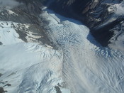English: Aerial view of the Franz Josef Glacier, looking down its length from above the tributary Melchior Glacier. On the far side of the valley, the small glacier that does not quite meet the Franz Josef is the Almer Glacier.