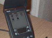 Palm IIIc personal digital assistant in its cradle.