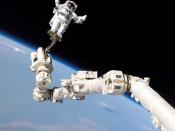 Astronaut Stephen K. Robinson, STS-114 mission specialist, anchored to a foot restraint on the International Space Station’s Canadarm2, participates in the mission’s third session of extravehicular activity (EVA). The blackness of space and Earth’s horizo