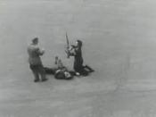 Screenshot from the movie, showing two Parisians (possibly FFI forces) disarming a recently killed German soldier. In the frames before this, the soldier is seen being shot, as Parisian snipers directly overlooking Notre-Dame Cathedral watch him die. In t