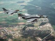 A U.S. Air Force McDonnell Douglas F-4G Phantom II Wild Weasel aircraft, foreground, and a General Dynamics F-16C Fighting Falcon aircraft of the 23rd Tactical Fighter Squadron, both assigned 52nd Tactical Fighter Wing, fly over Spangdahlem Air Base.