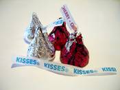 An arrangement of HERSHEY'S KISSES brand products. Two KISSES Milk Chocoltes and two KISSES Chocolates Filled with Cherry Cordial Creme.