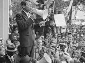 Attorney General Robert F. Kennedy speaking to a crowd of African Americans and whites through a megaphone outside the Justice Department; sign for Congress of Racial Equality is prominently displayed.