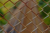 English: A pice of chain link fence over some railroad tracks