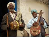Village musicians in Hyderabad singing and playing a drum and string instrument. The latter is decorated with swastika and aum signs.