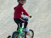 A boy riding a bicycle with training wheels