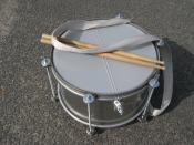 Samba Snare drum with its strap and a pair of wood sticks.
