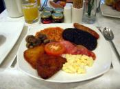 A full English breakfast with scrambled eggs, bacon, sausages, hash browns, and half a tomato