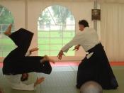 A classical aikido throw being practiced. Tori maintains balance and structure to throw uke, while uke safely takes a forward roll (mae ukemi).