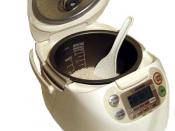 Electric rice cooker including scoop, containing uncooked rice