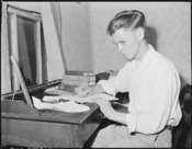 Louis Sergent, 16, who is in his first year at high school, does his homework. Both he and his father are determined... - NARA - 541288