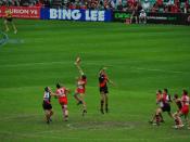 English: Darren Jolly (red and white) taps the ball to the rover Adam Goodes (37) after beating Patty Ryder (red and black) in the Ruck duel, while Jobe Watson (4) and Mark McVeigh block Luke Ablett and Brett Kirk (31) from the contest.