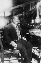 Marcus Garvey, National Hero of Jamaica, full-length, seated at desk