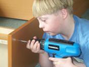 Boy with Down Syndrome using cordless drill to assemble a book case.