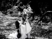 English: screenshot from Rashomon 1950 film 31:31 min. Toshirō Mifune as bandit Tajōmaru is standing, Machiko Kyō as Masago is kneeling and Masayuki Mori as samurai Kanazawa-no-Takehiro is sitting in the background