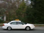 English: A student driver travelling southbound in a white Ford Taurus instructional vehicle on North Gregson Street in Durham, North Carolina.