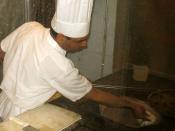 A chef working with a tandoor oven, a cylindrical clay oven used in cooking and baking