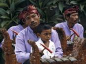 English: Child learning to play in a gamelan orchestra Nederlands: Dia. Theoretische muzieklessen zijn er voor dit kleine Balinese jongetje niet bij. Op de schoot van zijn vader zit hij tussen de andere spelers in het orkest. Af en toe mag hij het hamertj