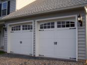 Sectional-type overhead garage doors in the style of carriage house doors. They are steel with exterior cladding.