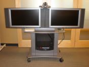 A Polycom VSX 7000 camera used for videoconferencing (top) with 2 video conferencing screens for simultaneous broadcast from 2 separate locations.