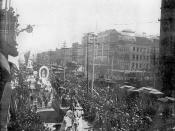 New Orleans Mardi Gras parade on Canal Street, early 1890s. View looking towards intersection of Chartres/Camp Street, with gazebo on neutral ground. Horse drawn floats on left side of street. Horse trams on neutral ground.