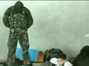 Masked hostage-taker standing on a dead man's switch during the second day of the crisis (a frame from the Aushev tape)