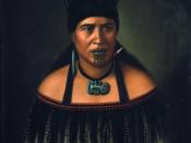 Hinepare, a woman of the Ngāti Kahungunu tribe. Shows a half-length portrait of a Maori woman wearing a hei-tiki around her neck, pounamu earring and shark tooth earring, and two huia feathers in her hair. She wears a cloak with black fringe border, and h