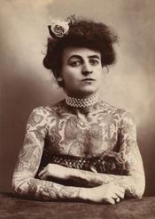 A woman showing images tattooed or painted on her upper body, 1907.
