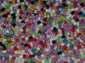 Close-up of a bucket full of midi-sized Hama beads in different opaque colors. The beads are 5mm in diameter and length.