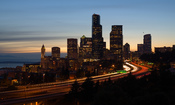 The skyline of Seattle, Washington at dusk. Interstate 5 is the freeway that cuts through downtown and Puget Sound is visible to the left.
