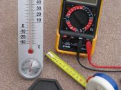 English: Four metric measuring devices - a tape measure, a thermometer, a one kilogram weight and an electrical multimeter. These instruments were selected to show some of the units of measure that are 