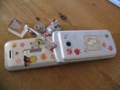 A Japanese cell phone with various stickers and charms attached to it.