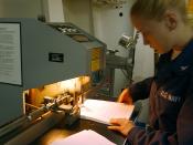 English: At sea aboard USS George Washington (CVN 73) Jun. 29, 2002 -- Lithographer's Mate 3rd Class Angel Flanagen from Central, TX, uses a paper drill to put together training manuals in the ship's print shop. George Washington is home ported in Norfolk