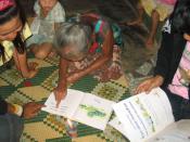 English: An elderly woman in a rural Lao village practices her reading skills. Written Lao is phonetic, and literacy rates are estimated at about 70%, but many adults read very slowly, if at all, because they've had little opportunity to see books. This w