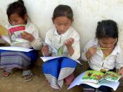 English: Three Lao girls sit outside their school, each absorbed in reading a book. This photo was taken after a rural school book party by Big Brother Mouse, a publishing and literacy project in Laos, which provides many children with their very first bo