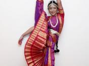 English: Bharat natyam dancer doing the split with one foot in the air.