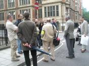 English: City visitors learn from an expert In Carey Street. Note the guide's official armband- this man has spent a year learning the history of probably the most historic square mile in the world.