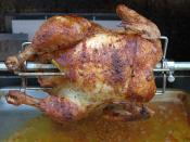 English: Chicken cooking on a gas grill rotisserie. The yellow protruding from the cavity is a pierced whole lemon.