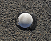 English: A round botts' dot (A type of raised pavement marker) photographed in Australia.