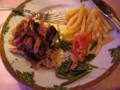 English: An andouillette sausage with the casing removed, displaying the contents. Green beans, French fries, and a tomato on the side. From a restaurant in Reims, France.