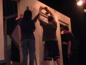 The tech crew constructs a set for Noises Off. The set designer (far right) explains how he wants it to look