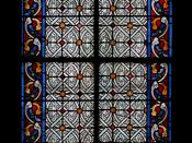 Français : Église Saint-Jean-Baptiste de Belleville, Paris 19 e arrondissement. Vitrail d'une chapelle. Bordure colorée, verrière blanche en grisaille. Par transparence, on voit la grille de protection.