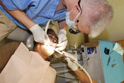 English: GUANTANAMO BAY, Cuba – Navy Cmdr. George Sellock, a dentist deployed with Joint Task Force Guantanamo’s Joint Troop Clinic, performs dental work on a Trooper’s tooth, May 13, 2009. The JTC is a first line aid station for JTF Guantanamo Troopers. 