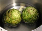 Globe artichokes being cooked with whole garlic cloves